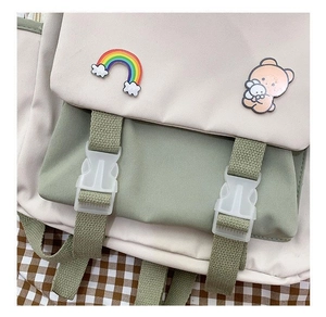 Detail of light green canvas backpack with cute bear badges and plastic buckle straps
