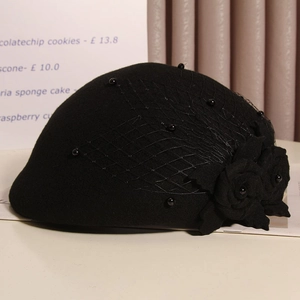 Detail of wool beret with black mesh veil, pearl accents and fabric rose ornaments