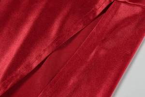 Detail of red satin dress featuring a high side slit and smooth silk texture fabric