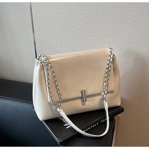 Detail of off-white PU leather bag featuring a silver chain strap and cylindrical metal lock