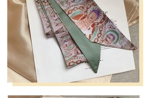 Detailed macro of the green and gold silk scarf with vintage Dunhuang mural art pattern