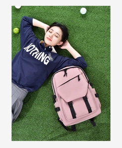 Pink canvas backpack with black buckles on grass background for outdoor leisure travel use