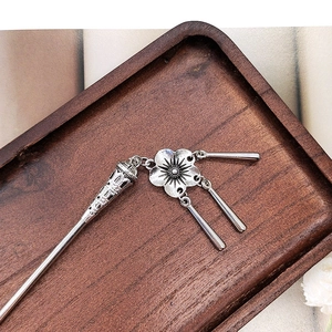 Detail of silver vintage hair stick with plum blossom and hanging metal tassels