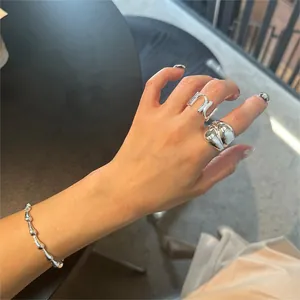 Close-up of minimalist S925 sterling silver U-shaped ring and beaded bracelet on hand