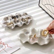 Close-up of irregular cloud-shaped ceramic jewelry trays in silver and white finishes