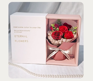 Detailed view of red soap flower bouquet in gift box with pink ribbons and white pearl decor