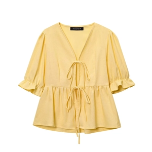 Detail of yellow V-neck top featuring puff sleeves with ruffles and front tie closure