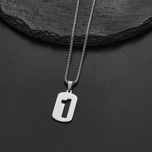 Detail of silver stainless steel number one pendant necklace on a dark stone background