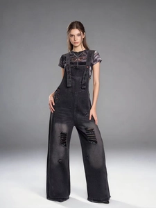 Close-up of distressed denim overalls with ripped details and wide leg cut in black finish