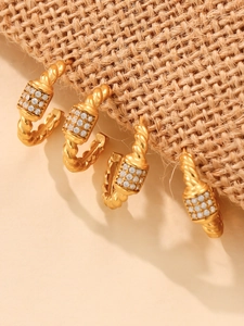 Detail of 18k gold plated twist earrings with sparkling triple row 5A zircon inlay on burlap