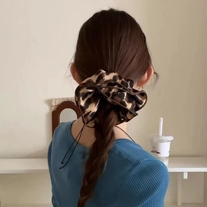 Macro shot of large leopard print satin scrunchie styled on a brunette low ponytail
