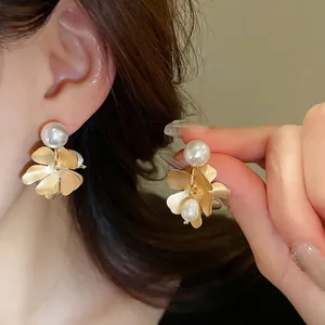Elegant gold flower earrings with freshwater pearls shown on a model for a vintage aesthetic