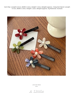 Detail of floral acetate hair clips with marble texture and pearl center on a wooden tray