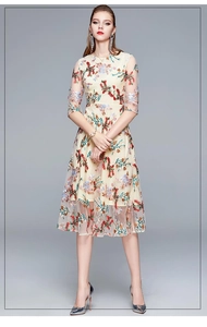 Close-up of elegant apricot mesh dress featuring intricate floral embroidery and sheer sleeves