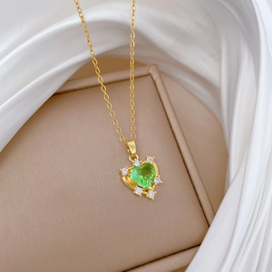 Gold titanium steel necklace with green heart zirconia pendant on a beige jewelry box
