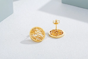 Macro detail of golden circular cutout earrings with fine floral pattern engraving