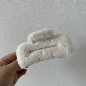 Detail of plush faux fur hair claw clip in cream white showing soft fuzzy texture