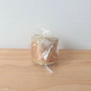 Close-up of bronze ribbon roll with gold glitter patterns in transparent packaging