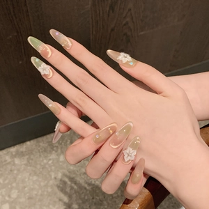 Detail of peach-lime cat eye press-on nails with 3D floral accents and rhinestones