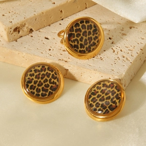 Close-up of leopard print jewelry set with ring and earrings on a textured stone