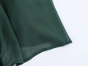 Detail of dark green velvet dress hem showing precise stitching and sheer fabric texture