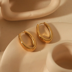 Polished 18k gold plated U-shaped geometric earrings on a beige ceramic surface