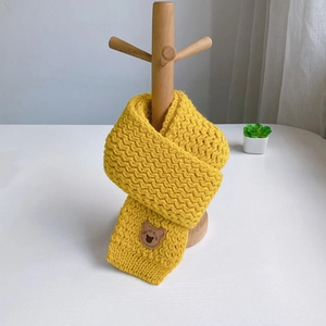 Detail view of ginger yellow knit scarf with cute brown bear embroidery for toddlers