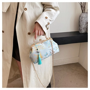 Elegant light blue evening bag with floral embroidery, gold handle and tassel charm.