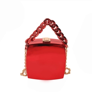 Glossy red hard shell handbag with thick chain handle and gold shoulder strap on white