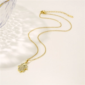 Collier Main de Fatma dorée avec zircons micro-paves sur fond clair ondulé