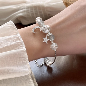 Close-up of star and moon charm bracelet with crystals and grey beads on woman wrist