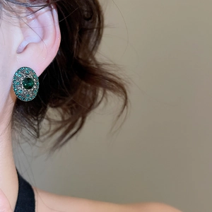 Close-up of vintage oval emerald rhinestone stud earrings with antique bronze metal base