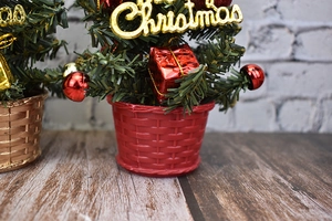 Mini green Christmas tree with red base and festive ornaments for tabletop decoration
