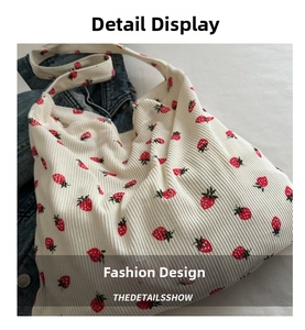 Detail view of cream white corduroy tote bag featuring vibrant red strawberry patterns