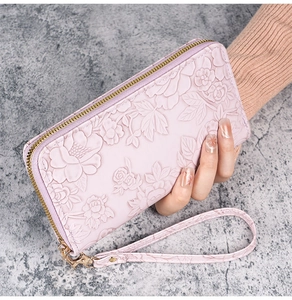 Detail of pink long wallet featuring 3D floral embossing and gold zipper with wrist strap