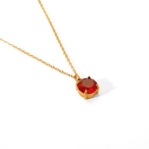 Macro detail of the gold-plated chain with a four-prong set round red gemstone pendant