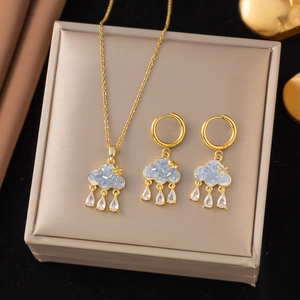 Golden necklace and earrings set with light blue cloud pendants and raindrop stones