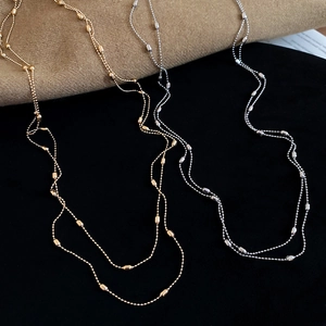 Detailed view of layered gold and silver beaded necklaces with polished metallic texture
