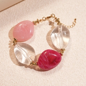 Detail of acrylic marbled beads in pink and red with golden rings and lobster clasp