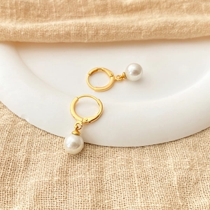 Elegant 18K gold plated hoop earrings with white shell pearls on a minimalist display