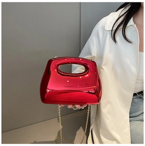 Detail of red acrylic evening bag with integrated hollow handle and gold chain strap