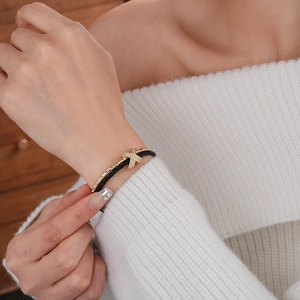 Detailed close-up of gold plated crisscross charm with pavé cubic zirconia on black cord