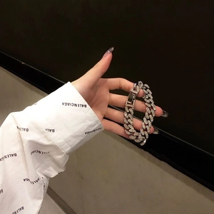 Bracelet gourmette argenté serti de strass porté au poignet avec une pose élégante