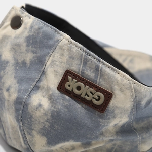 Detail of blue and white tie-dye canvas hat with brown CSIOR rubber tag and metal button