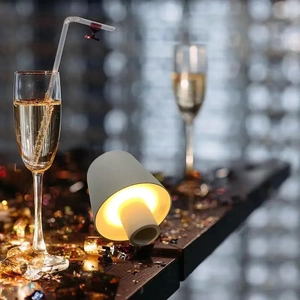 Portable mushroom LED lamp with warm light on a champagne bottle in a festive setting