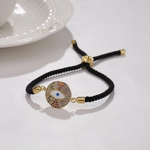 Makro-Detail des vergoldeten Evil Eye Anhängers mit bunten Zirkonia auf schwarzem Band