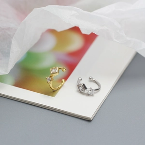 Detailed close-up of gold and silver ear cuffs with square and round zircon settings
