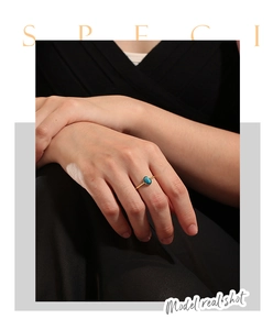 Close-up of bohemian gold ring featuring an oval turquoise stone worn on a finger