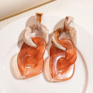 Flat lay view of amber and cream acrylic chain link earrings on a white tray
