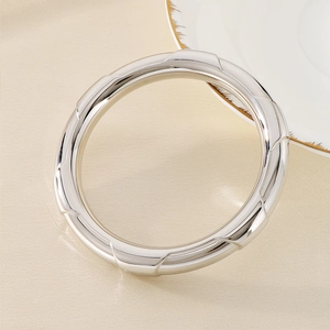 Detailed view of polished silver stainless steel hollow bangle on premium silk fabric